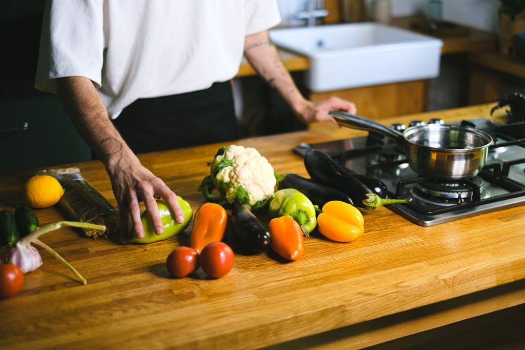 Close-up of a chef arranging fresh vegetables on a wooden kitchen counter for a healthy meal.