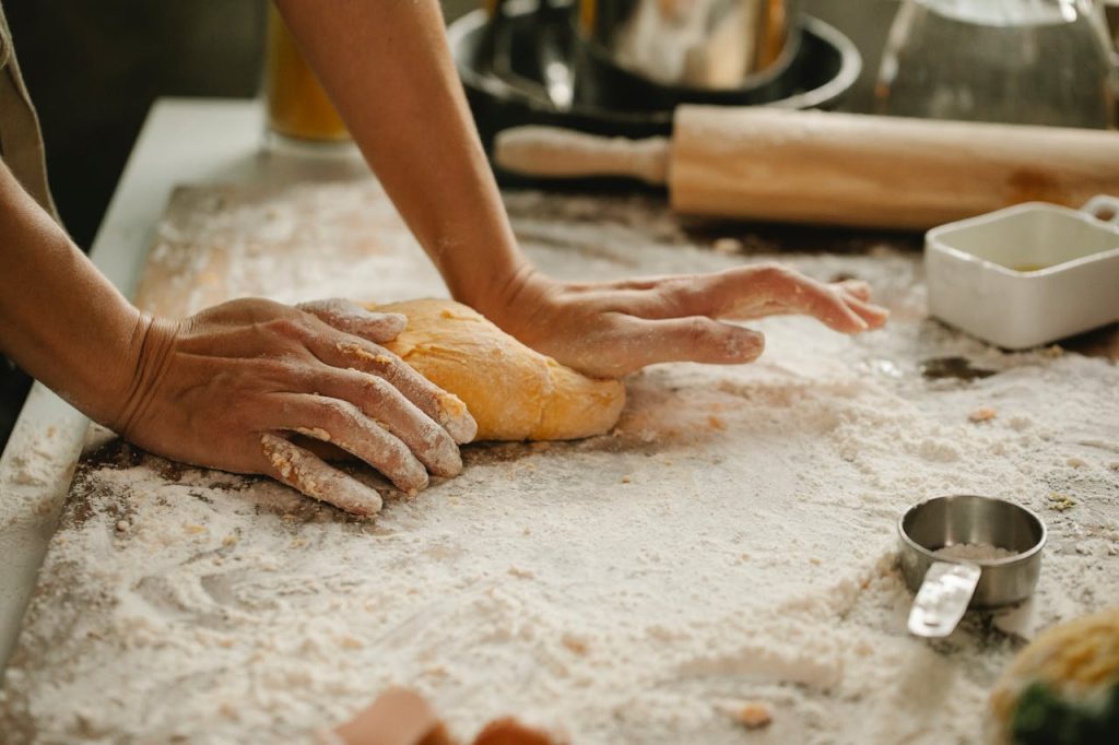 A person kneads fresh dough in a kitchen, showcasing the baking process.